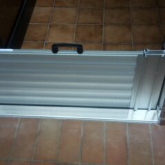 Aluminium-Türschwelle mit einem Klappmechanismus, der an einer Tür montiert ist.