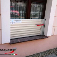 Hochwasserschutzsystem von Acquastop, installiert an einem Fenster mit einem roten Griff.
