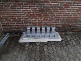 Sechs transparente Lichtschachtabdeckungen aus Kunststoff auf einer Betonplatte.