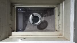 Rundes Bullauge mit transparentem Glas in einer Wandöffnung, sichtbar von der Innenseite.