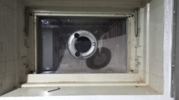Rundes Bullauge mit transparentem Glas in einer Wandöffnung, sichtbar von der Innenseite.