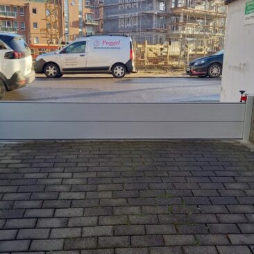 Eine graue Sicherheitsbarriere, die den Zugang zu einer Einfahrt blockiert.
