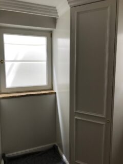 Weißer Wandschrank neben einem Fenster mit einem schlichten Design in einem Raum.