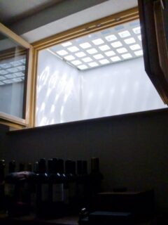 Lichtschachtabdeckung mit Gitterstruktur, die Tageslicht durchlässt, sichtbar durch ein Fenster.