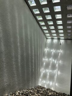 Lichtschachtabdeckung mit transparenten Elementen und Kies auf dem Boden.