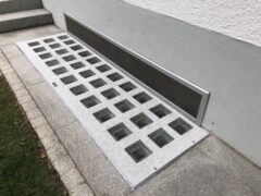 Lichtschachtabdeckung mit transparenten Glassteinen und Insektenschutzgitter.