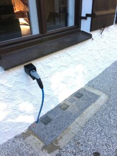 Lichtschachtabdeckung mit einem Anschluss für eine elektrische Verbindung an einer Wand.