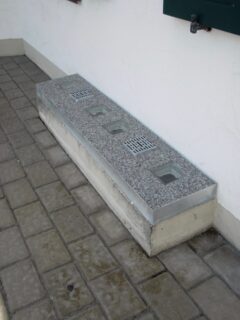 Beton Lichtschachtabdeckung mit mehreren Gittereinsätzen in einer geraden Form.