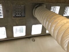 Rohrleitung, die durch eine Lichtschachtabdeckung führt, mit sichtbaren Lüftungsgittern.