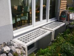 Betonlichtschachtabdeckungen mit Glasoberfläche vor einem Fenster in einem Wohngebäude.