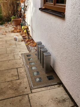 Entwässerungssystem mit fünf Edelstahlrohren und einer betonierten Fläche zur Wasserableitung.